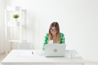 Young woman using phone while sitting on table