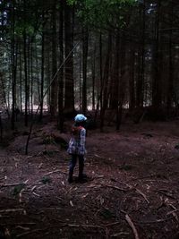 Full length of woman standing on tree trunk in forest