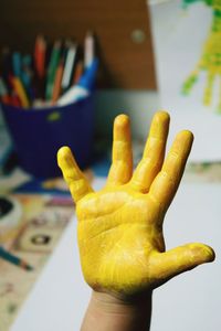 Cropped image of child with yellow painted hand