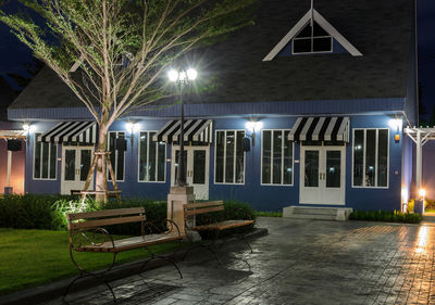 Empty chairs and tables in illuminated building at night