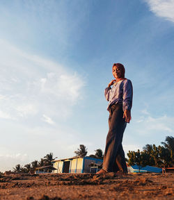 Low angle view of woman standing on land against sky