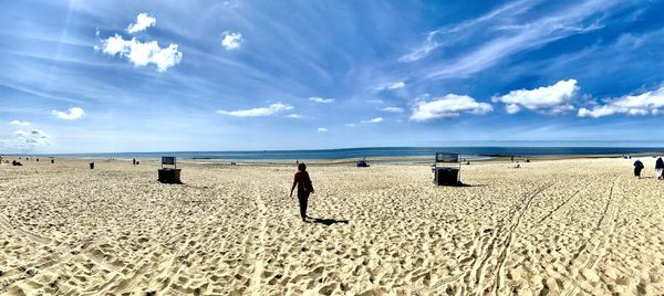 Rear view of man on beach against sky