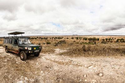 Car on landscape against cloudy sky