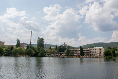 Buildings by river against sky