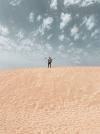 Man standing on sand dune in desert against sky