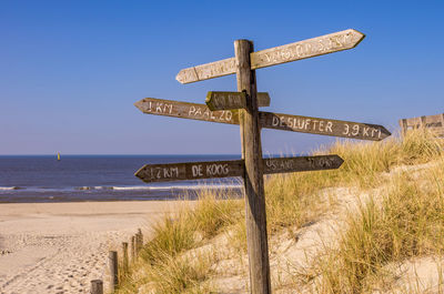 Cross sign on beach against clear sky