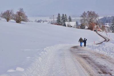 People walking on snow covered trees against sky