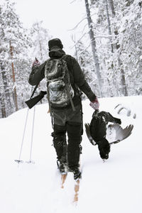 Rear view of people walking on snow during winter