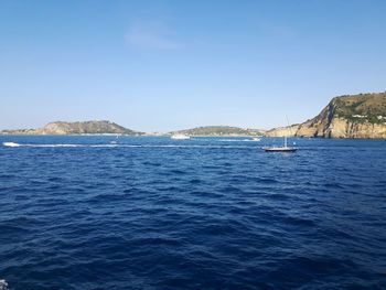 Sailboats sailing in sea against clear blue sky