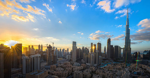 Modern buildings in city against sky during sunset