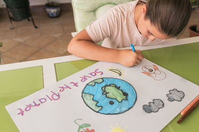 Girl making poster of environmental issues at home