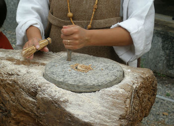 Midsection of woman working on ancient grinder