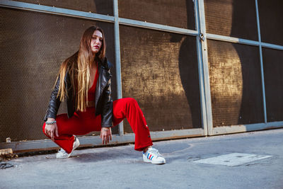 Full length of young woman standing against wall