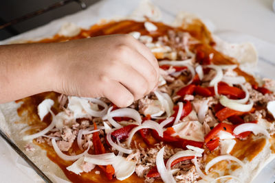 Close-up of hand preparing pizza