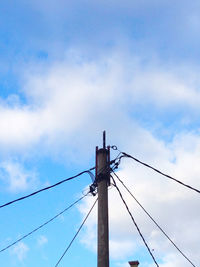 Low angle view of electricity pylon against blue sky