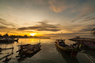 Boats moored in sea against sky during sunset