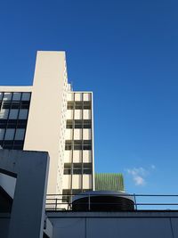 Low angle view of modern building against blue sky