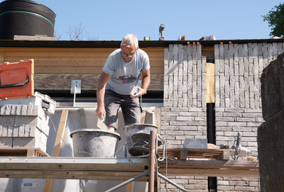 Masonry worker the bricklayer makes the facade of the house from gray bricks