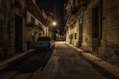 Car parked in alley amidst buildings in city