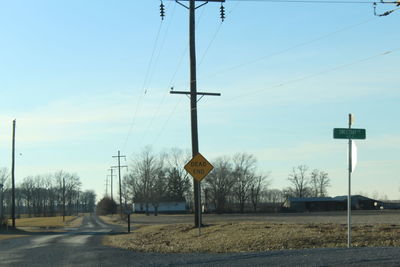 Road sign by street against sky