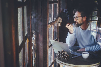 Mature man smoking while looking through window