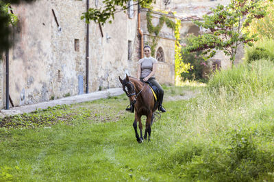 Woman riding on horse at grass area