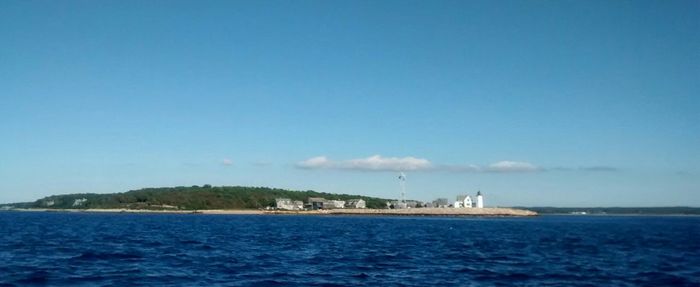 Boat sailing on sea against blue sky