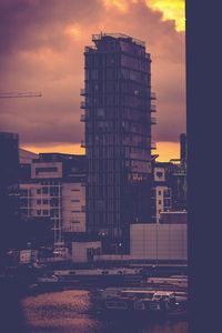 Buildings in city against dramatic sky during sunset