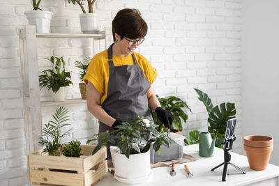 Side view of woman holding potted plant