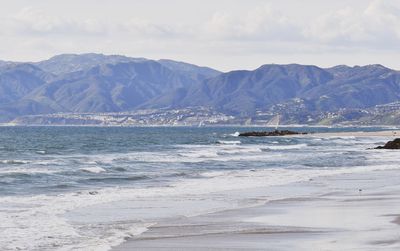 Scenic view of sea and mountains against sky