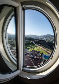 Landscape against clear sky seen from circle window at hotel