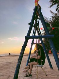 Low angle view of children playing on beach against sky during sunset