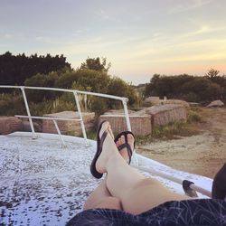 Low section of woman sitting against sky