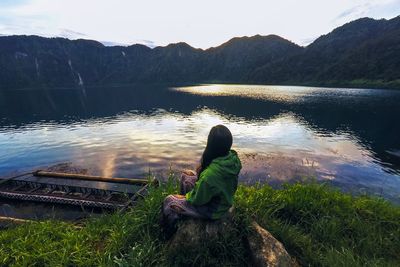 Rear view of woman looking at lake against mountain