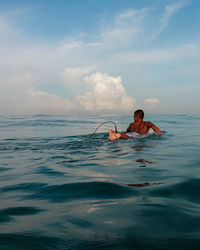 Full length of shirtless man in sea against sky