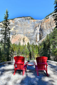 Empty chair in forest against clear sky