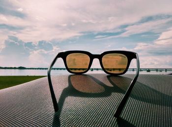 Close-up of sunglasses against sky at sunset