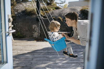 Mother swinging daughter