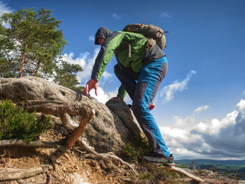 Man climbing steep mountain slope. sunny windy day in rocks.