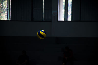 Volleyball in mid-air against windows