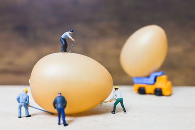 Close-up of figurines with eggs and toy trucks on table