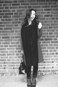 Full length of woman standing against brick wall