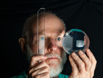 Portrait of man holding camera over black background