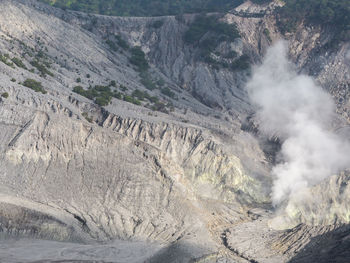 High angle view of smoke emitting from volcanic mountain