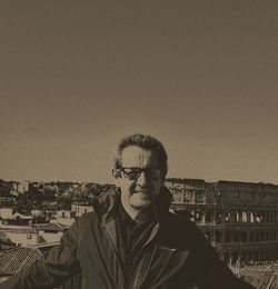 Portrait of young man standing against sky in city