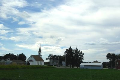 Trees on field against cloudy sky