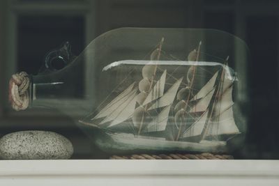 Close-up of miniature ship on bottle seen through glass