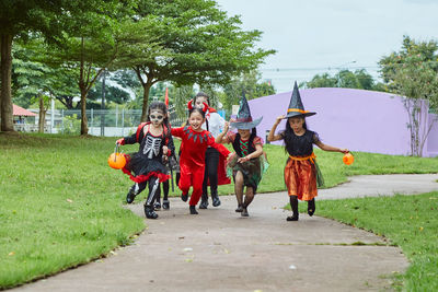 Girls in costumes running on footpath during halloween