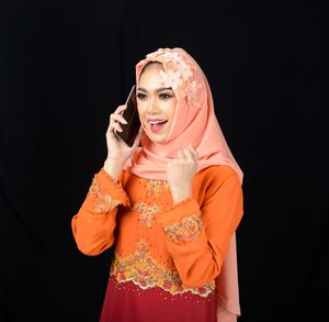 Midsection of smiling woman standing against black background