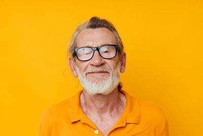 Portrait of smiling senior man against yellow background